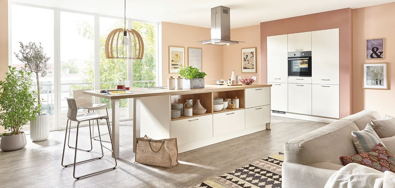 Cuisine beige ouverte avec mur rose poudré et îlot prolongé en table