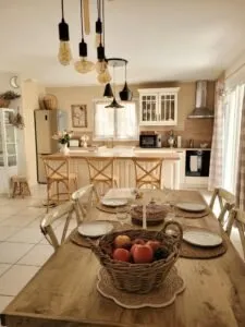 Cuisine équipée de style campagnard avec îlot central, suspensions noires et grande table en bois
